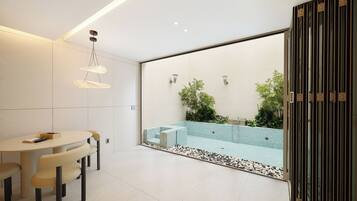 A modern bathroom with a glass-enclosed shower, a round table with chairs, and a minimalist design.