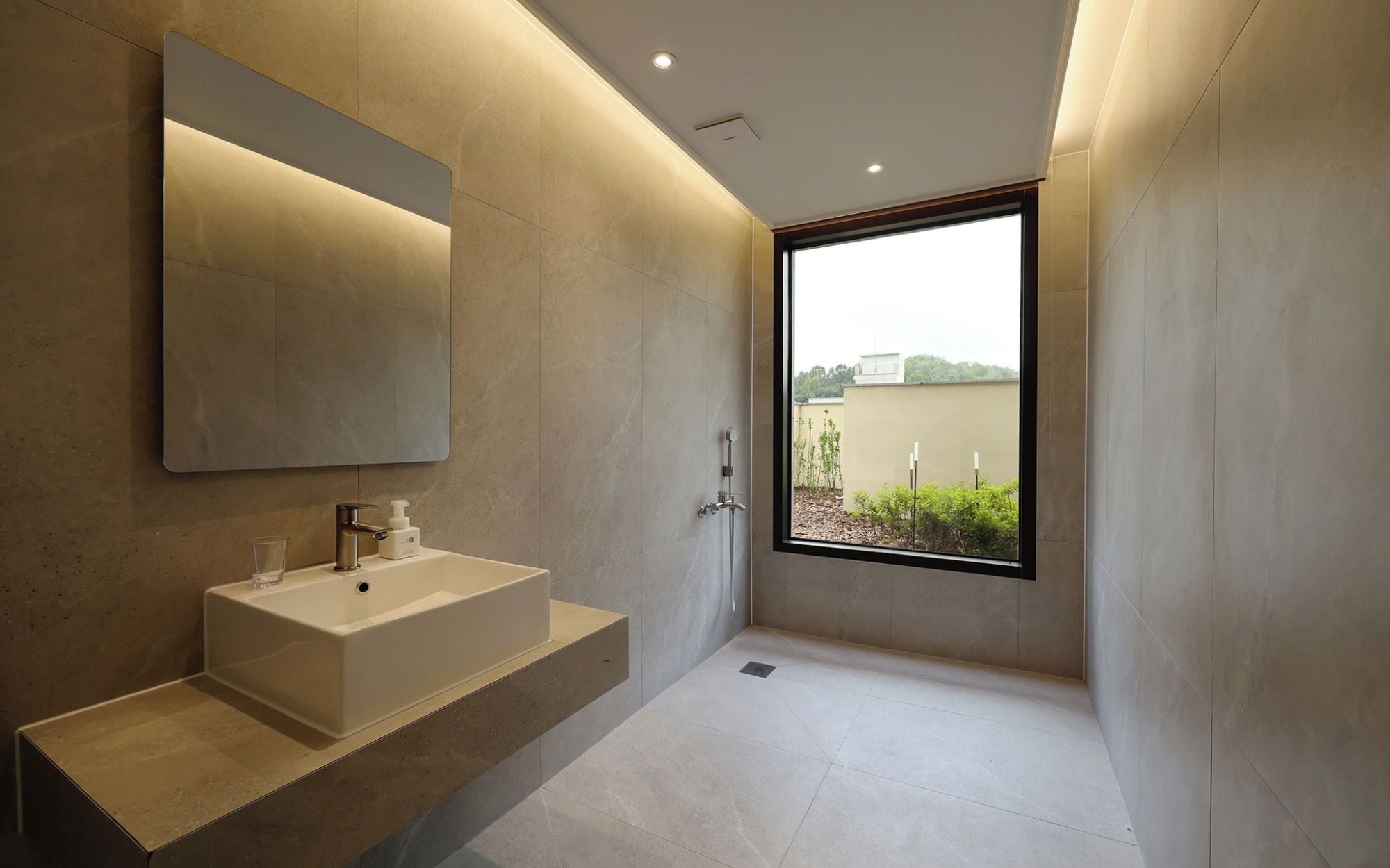 A modern bathroom with a large mirror, a bathtub, and a shower.