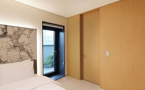 A bedroom with a bed, a door leading to a balcony, and a marble wall.