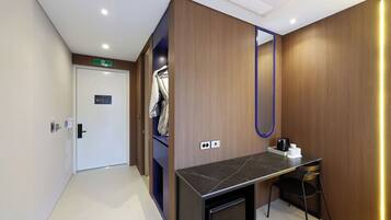 Une chambre d’hôtel avec un mur en bois, un bureau avec une chaise, un miroir et une machine à café.