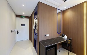 A hotel room with a wooden wall, a desk with a chair, a mirror, and a coffee machine. - HotelTheDeisngers SNU (Seoul)