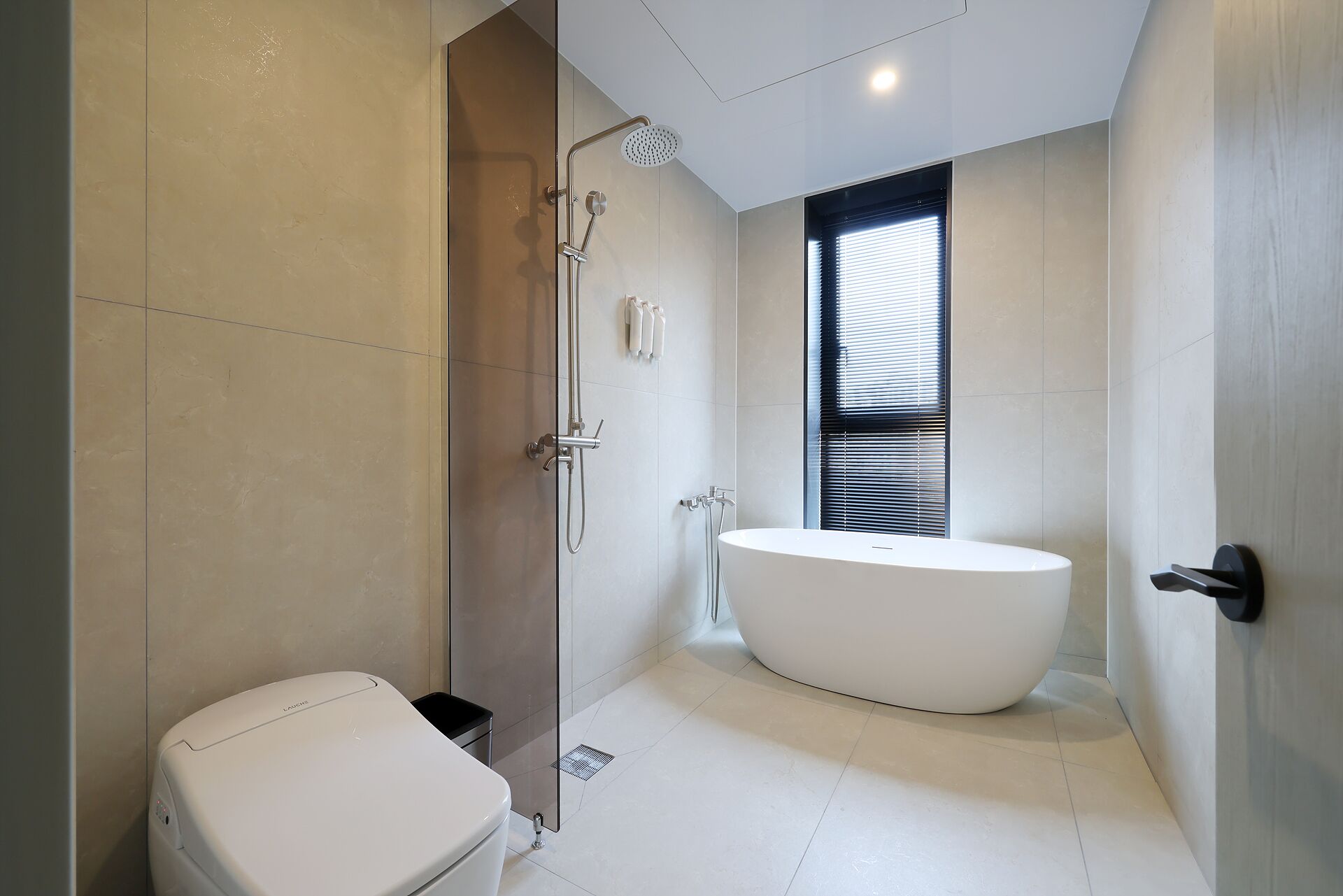 A modern bathroom with a glass-enclosed shower, a freestanding bathtub, and a toilet.