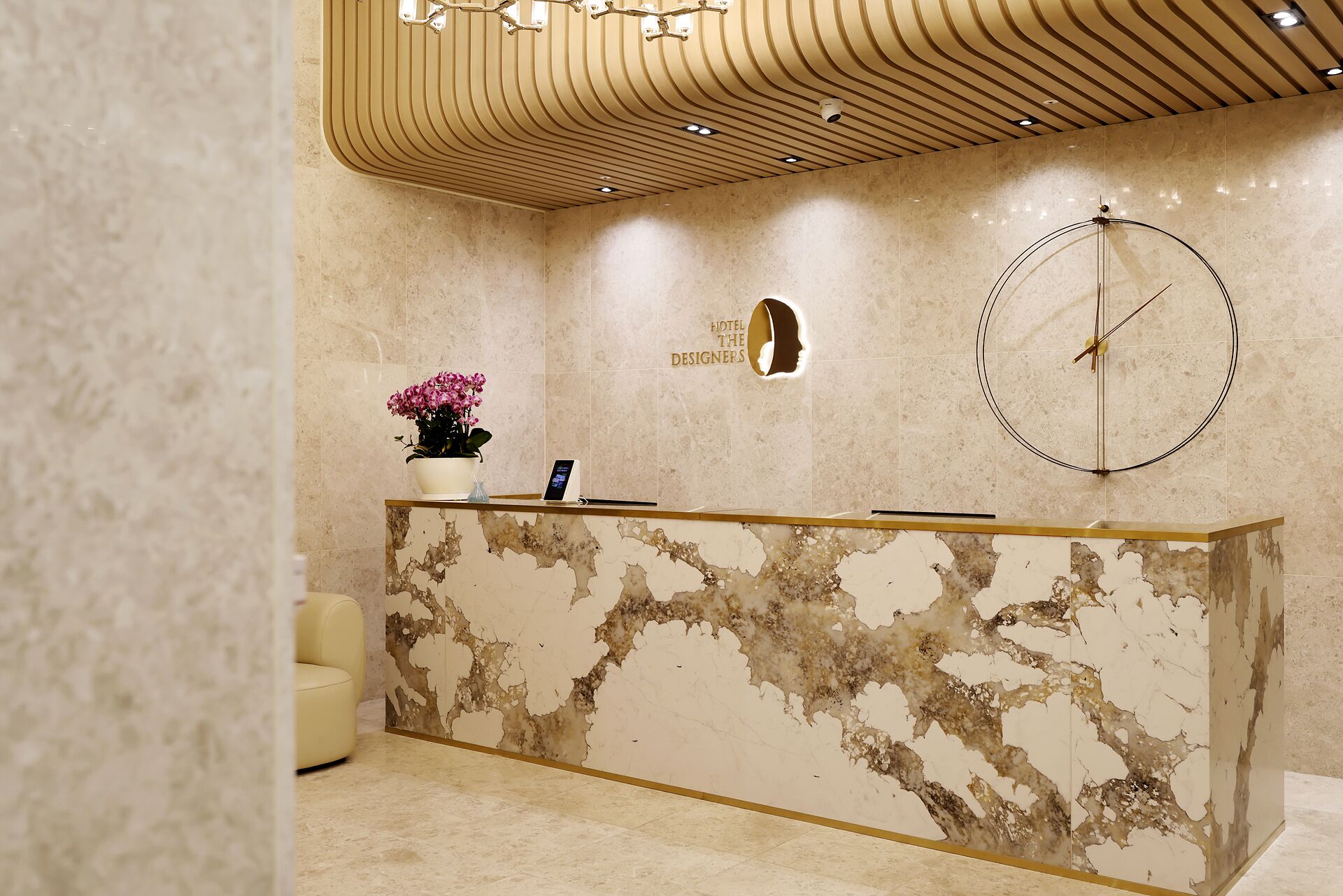 Un mostrador de recepción de hotel con diseño de mármol, un reloj y una planta en maceta.