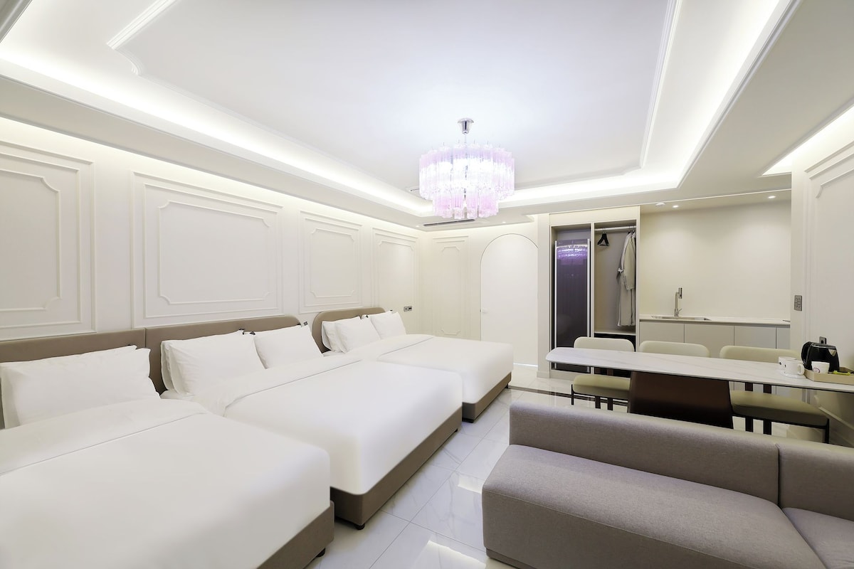 Una habitación de hotel con una cama grande, un sofá, una mesa de comedor y una araña.