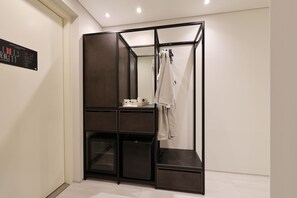 A compact room with a wardrobe, a small table with a cup, and a hanging rack with clothes. - HotelTheDeisngers SNU (Seoul)