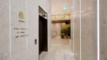 A hotel lobby with a marble floor, a reception desk, and a sign indicating guest rooms and hotel lounge locations.