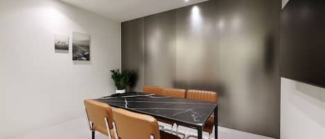 A modern conference room with a black marble table, leather chairs, and a potted plant.