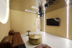 A modern interior with a sofa, a round gold table, a flat-screen TV, and a door. - HotelTheDeisngers SNU (Seoul)