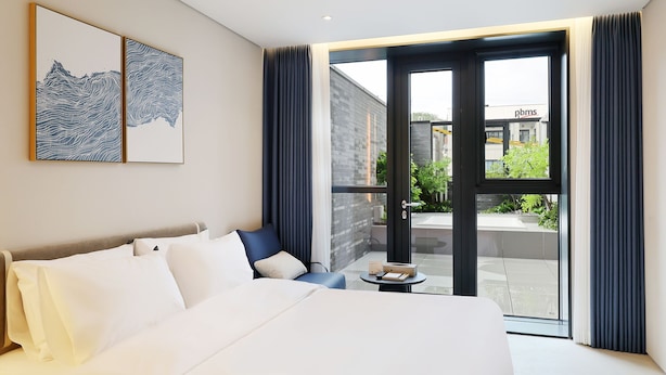 A hotel room with a large bed, a small table, and a view of the outside.