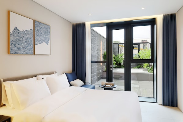 Habitación de hotel con una cama grande, una mesita y vistas al exterior.