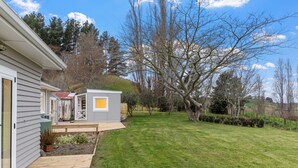 A residential property with a wooden deck, a small shed, and a well-maintained lawn.