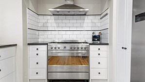 A compact kitchen with white cabinetry, a stainless steel stove, and a built-in oven.