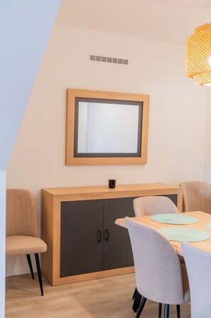 A dining area with a wooden table, chairs, a cabinet, and a wall-mounted mirror.
