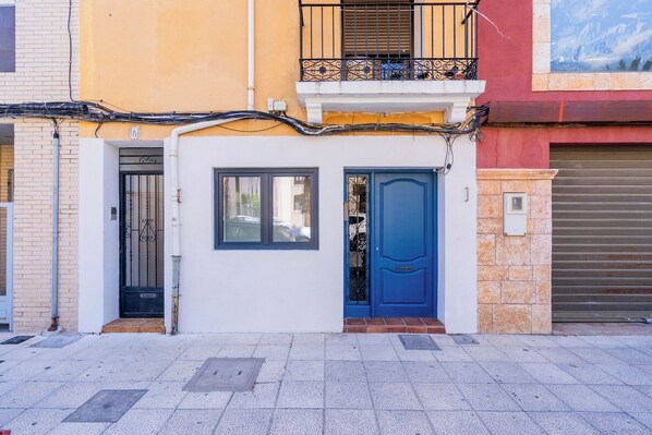 A building with a blue door, a window, and a balcony with a railing.