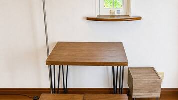 A dining area with a table and benches, a floor lamp, and a window with a view of greenery.