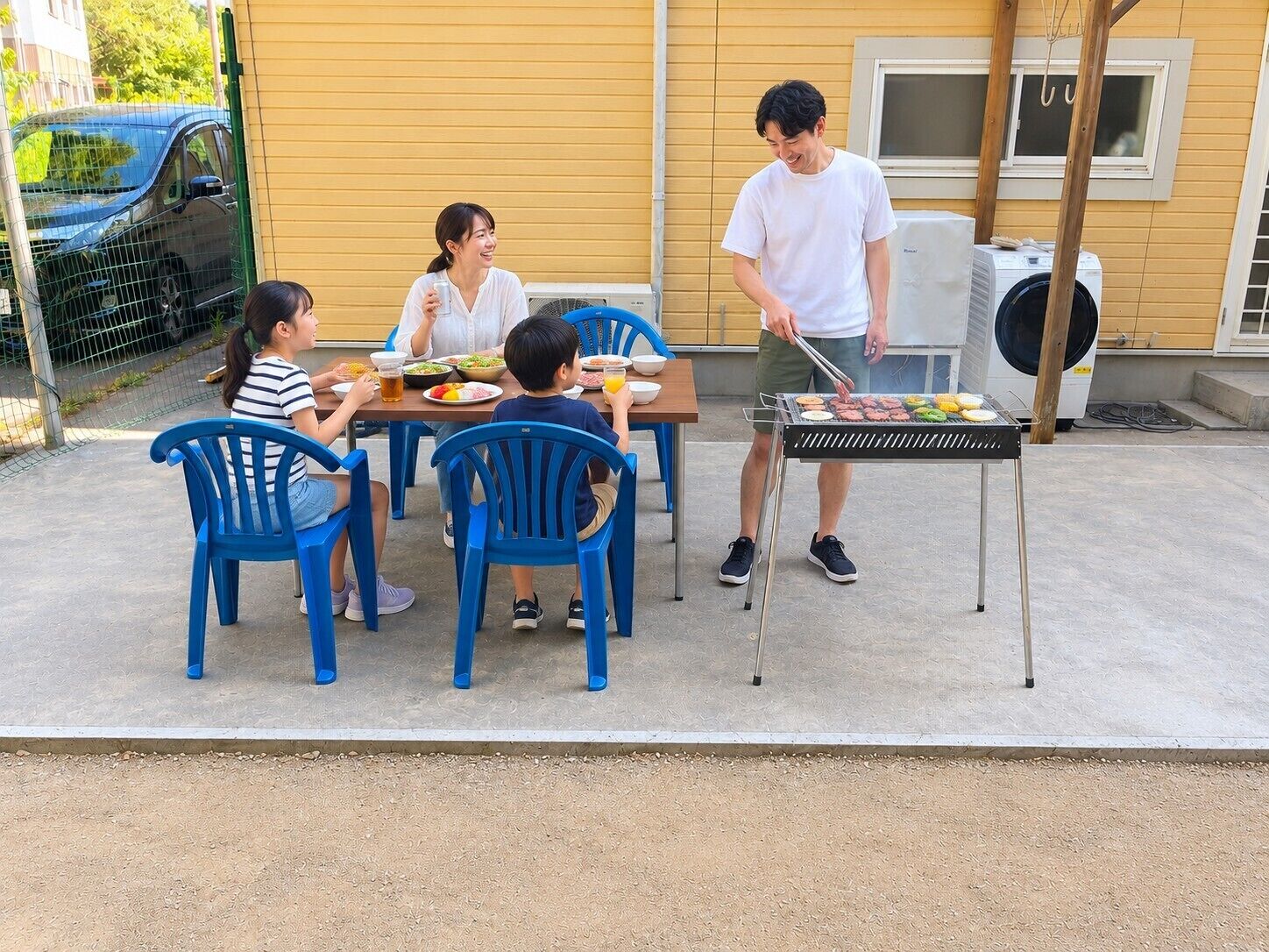 Una famiglia cena all'aperto con una griglia, sedie e un tavolo.