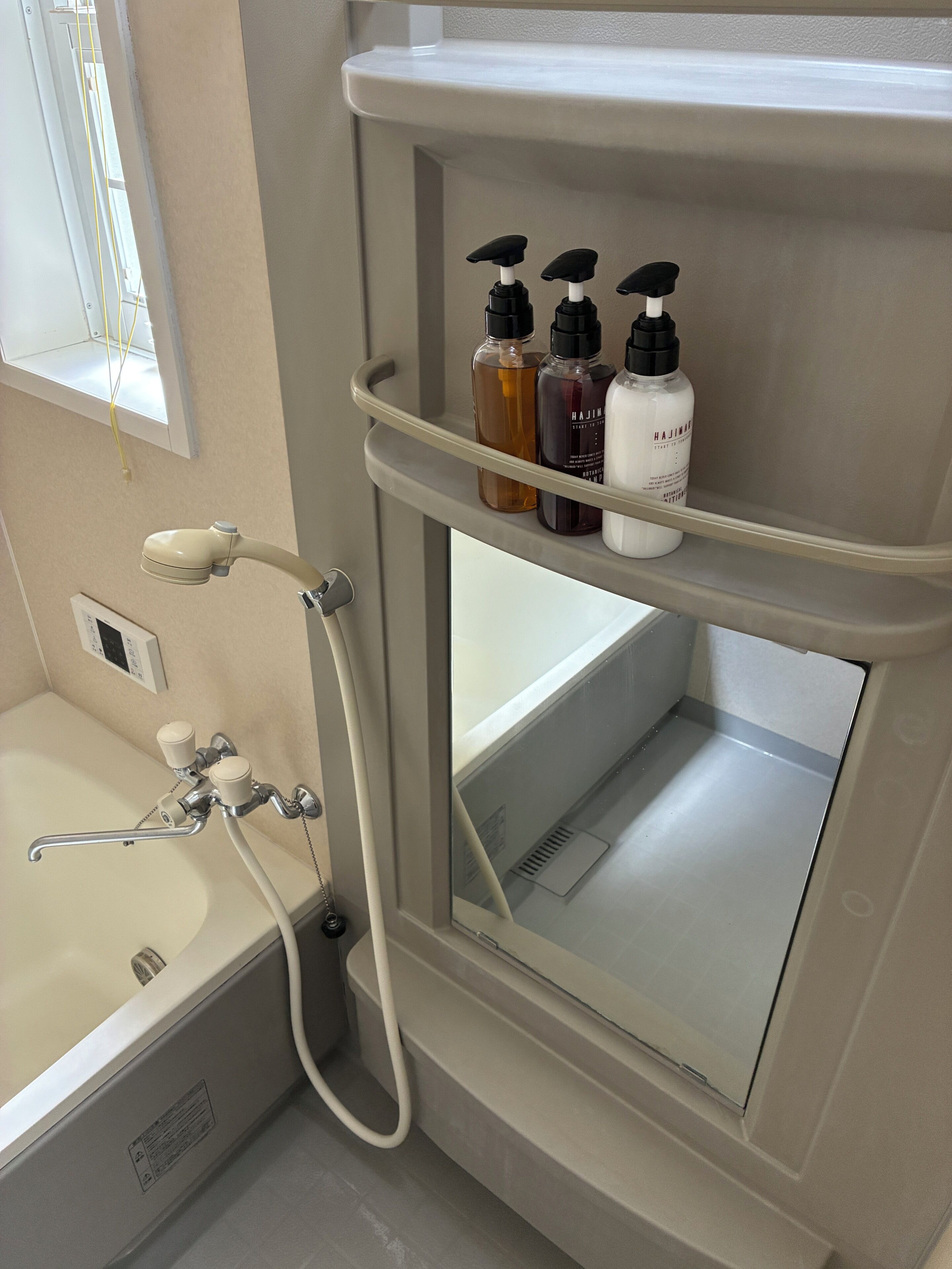 A bathroom with a bathtub, a shower, and a shelf with toiletries.