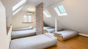 A dormitory-style room with three bunk beds, skylights, and a brick accent wall.