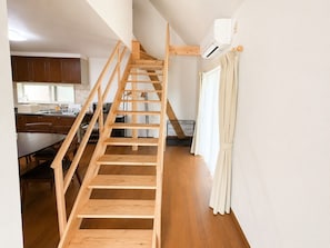 A wooden staircase leading to a loft bedroom with a view of the kitchen.
