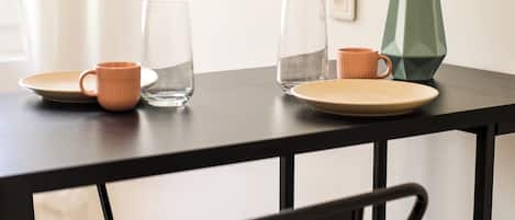 A table with a vase of flowers, two cups, and a glass.