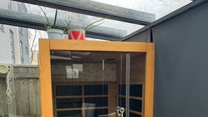 A sauna with a wooden frame, glass doors, and a bench inside.