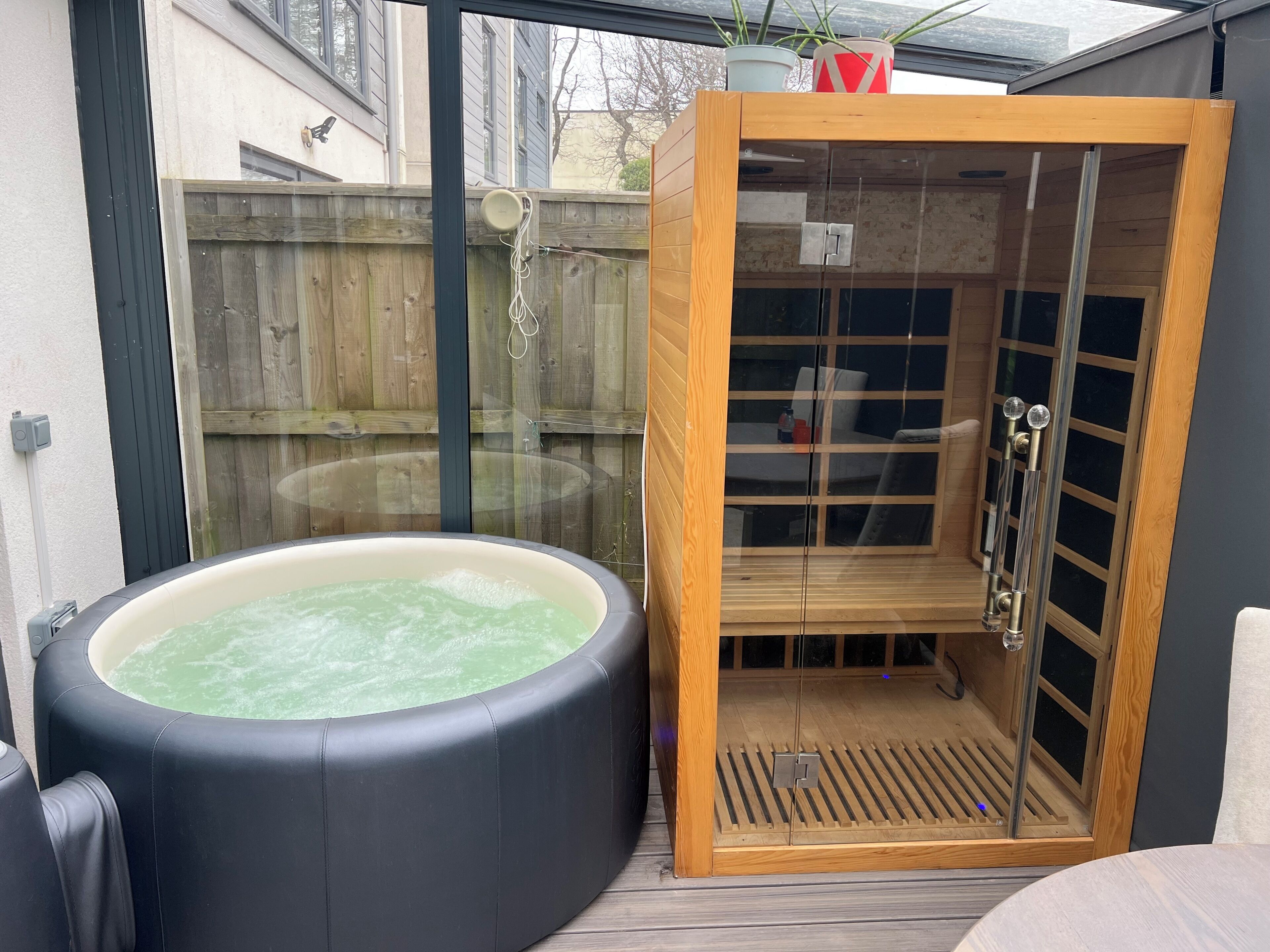 A hot tub and a sauna in a wooden enclosure with glass doors.
