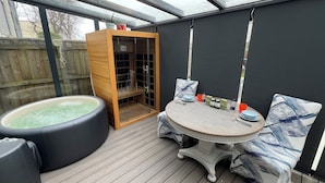 A spa area with a hot tub, wooden sauna, and a table with seating.