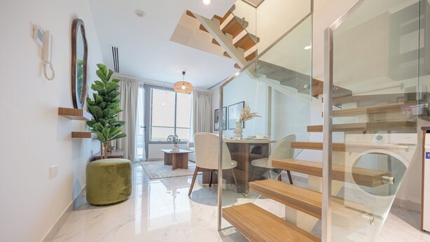 A modern interior with a staircase, a dining area, and a living space. - Bloomfields 2br Duplex in Oasis 1  (Abu Dhabi)