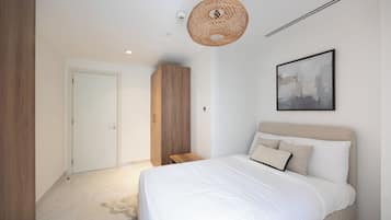A bedroom with a bed, a wardrobe, a door, a hanging light fixture, and a framed picture on the wall.