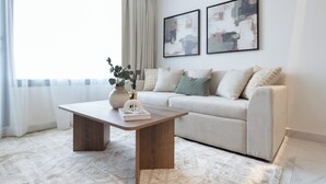 A modern living room with a sofa, a coffee table, and two abstract paintings on the wall. - Bloomfields 2br Duplex in Oasis 1  (Abu Dhabi)