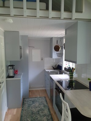 A compact kitchen with a built-in oven, a sink, and a stove. There is a small refrigerator and a coffee maker on the counter. - Cottage Above Falu Gruva With Wood Burning Sauna (Falun)