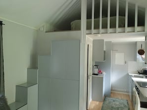 A compact kitchen with a built-in oven, a small sink, and a coffee maker.