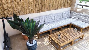 Ein moderner Außenbereich mit einer gepolsterten Couch, einem Holztisch und einer Zimmerpflanze.