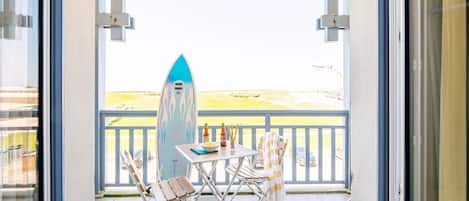 A balcony with a surfboard, a table, and two chairs.