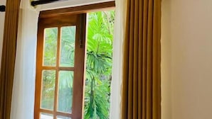 A room with a window, curtains, and an air conditioning unit.