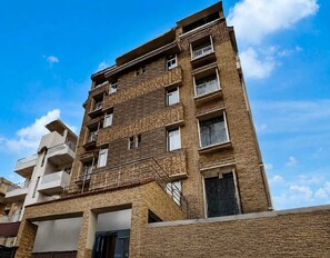 Ein mehrstöckiges Gebäude mit Balkonen und einer Ziegel-Fassade unter blauem Himmel.