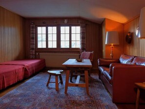 Una habitació amb llit, taula, cadira, sofà i làmpada.