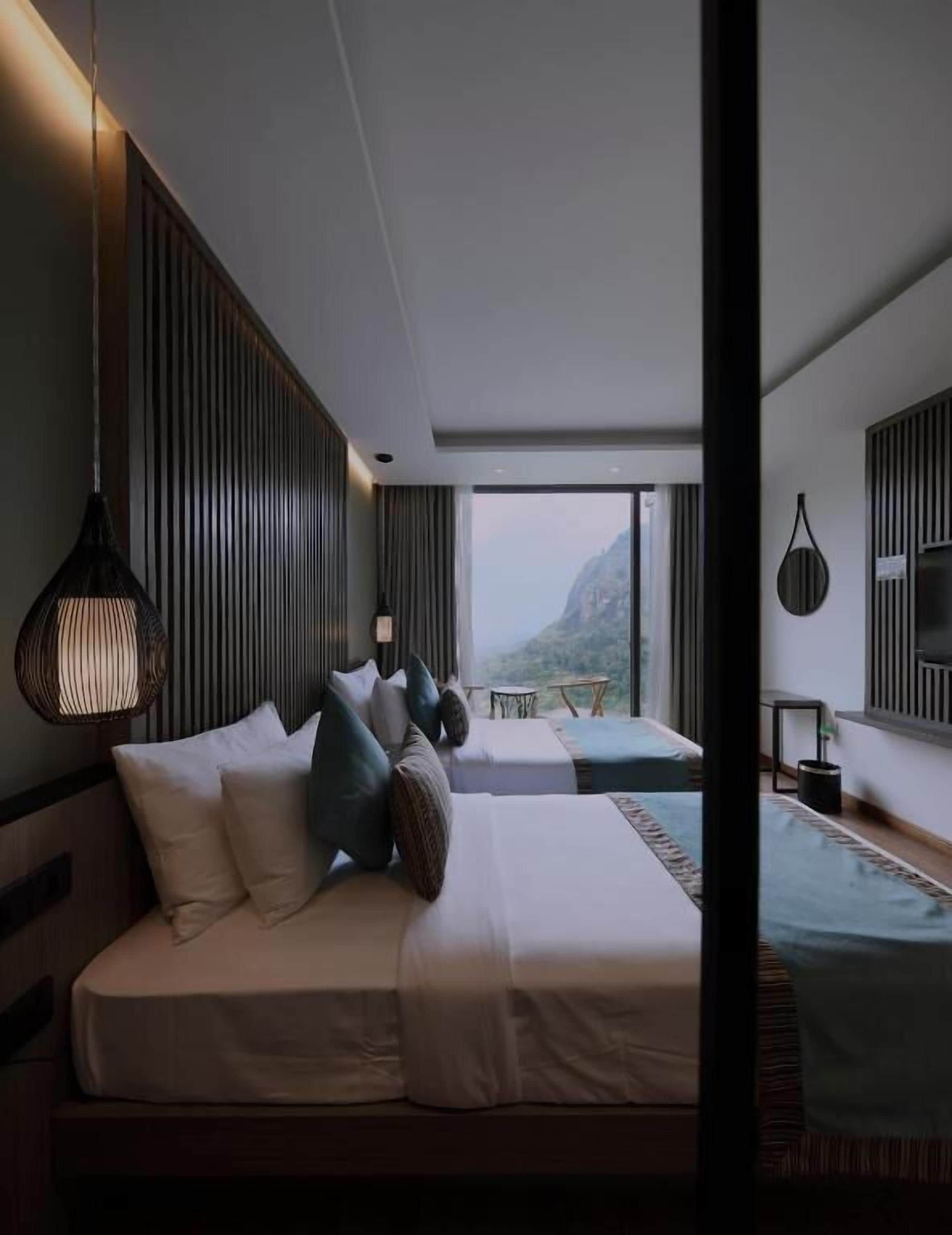Habitación de hotel moderna con una cama grande, una cama más pequeña y vistas a la montaña.