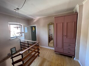 A room with a wooden floor, a large wardrobe, a mirror, and a window with a hanging light fixture. - Casa Vinea – a getaway in the heart of the Saale-Unstrut wine region. (Freyburg (Unstrut))