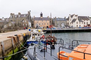 A harbor with boats docked, a stone building with a clock tower, and a row of houses. - Modern, Bright Studio in the Heart of Lerwick (Lerwick)