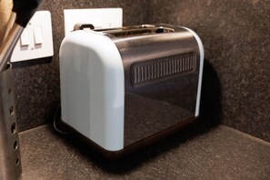 A toaster on a countertop with a power outlet nearby. - Modern, Bright Studio in the Heart of Lerwick (Lerwick)