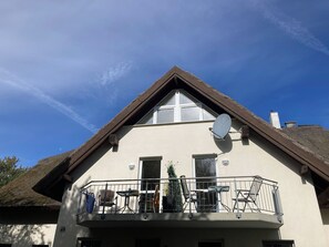 A two-story building with a balcony, satellite dish, and a thatched roof. - Seaside air, expansive scenery, and time for yourselves—Strandstudio Strandhafer in Lobbe (Mönchgut)