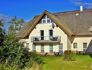 A two-story building with a balcony on the second floor, a flat roof, and a well-maintained lawn. - Seaside air, expansive scenery, and time for yourselves—Strandstudio Strandhafer in Lobbe (Mönchgut)
