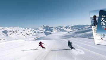 Pista d'esquí amb esquiadors i un gran anunci de Zillertaler Super Skipass.