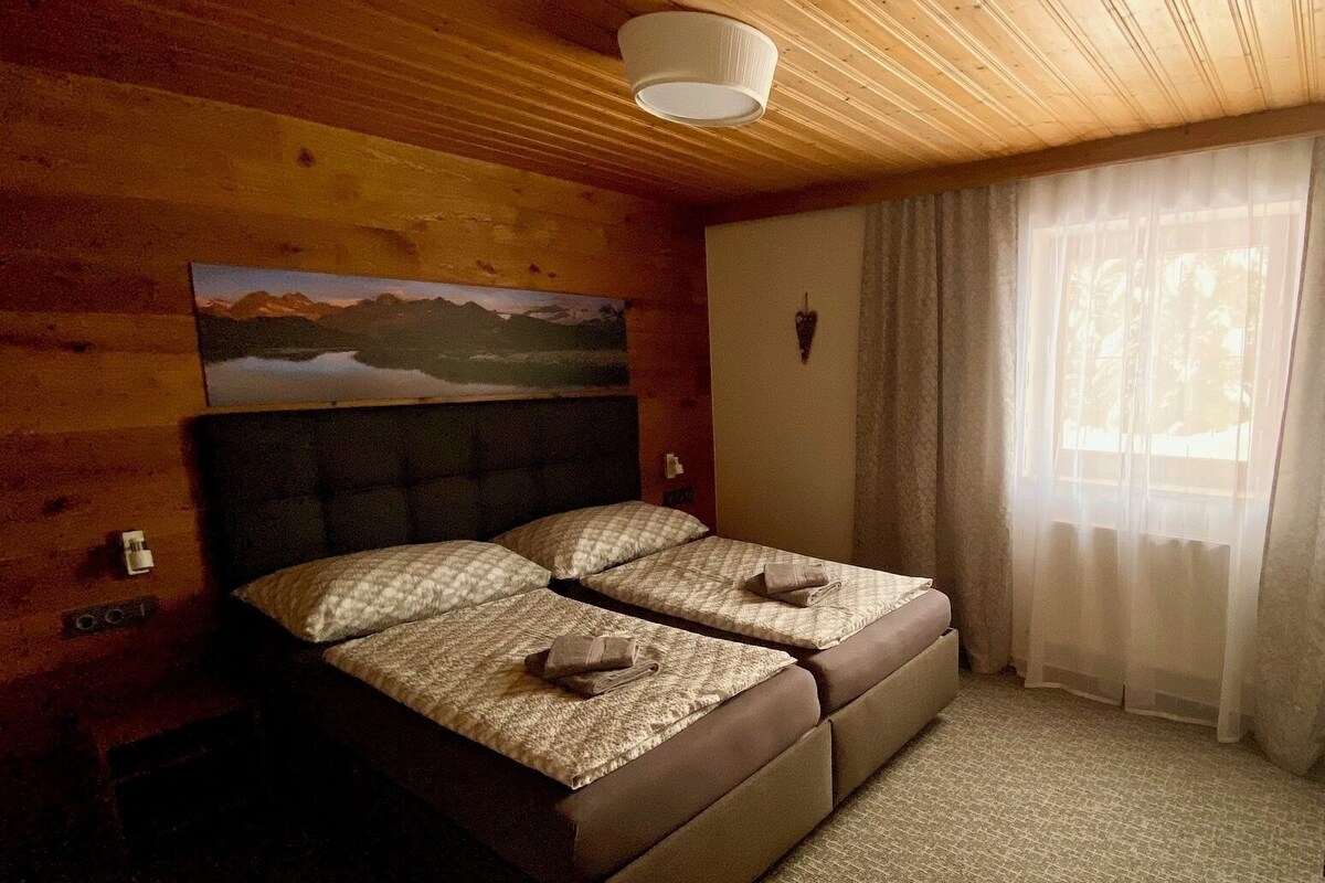 A room with a bed, a painting on the wall, and a window with curtains.