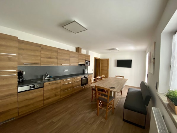 A modern kitchen with wooden cabinets, a dining table, and chairs.