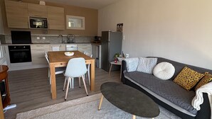 A modern kitchen with built-in appliances, a dining area with a table and chairs, and a living area with a sofa and a coffee table. - A cozy, fully equipped home with a breathtaking view (Vernet-les-Bains)