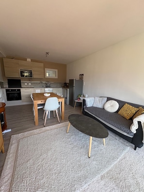 A modern kitchen with built-in appliances, a dining area with a table and chairs, and a living area with a sofa and a coffee table. - A cozy, fully equipped home with a breathtaking view (Vernet-les-Bains)