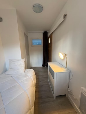 A bedroom with a bed, a desk with a lamp, a window, and a door leading to another room. - A cozy, fully equipped home with a breathtaking view (Vernet-les-Bains)