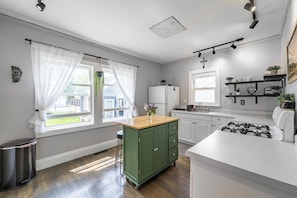 A modern kitchen with a green cabinet, white countertops, and a stainless steel stove.